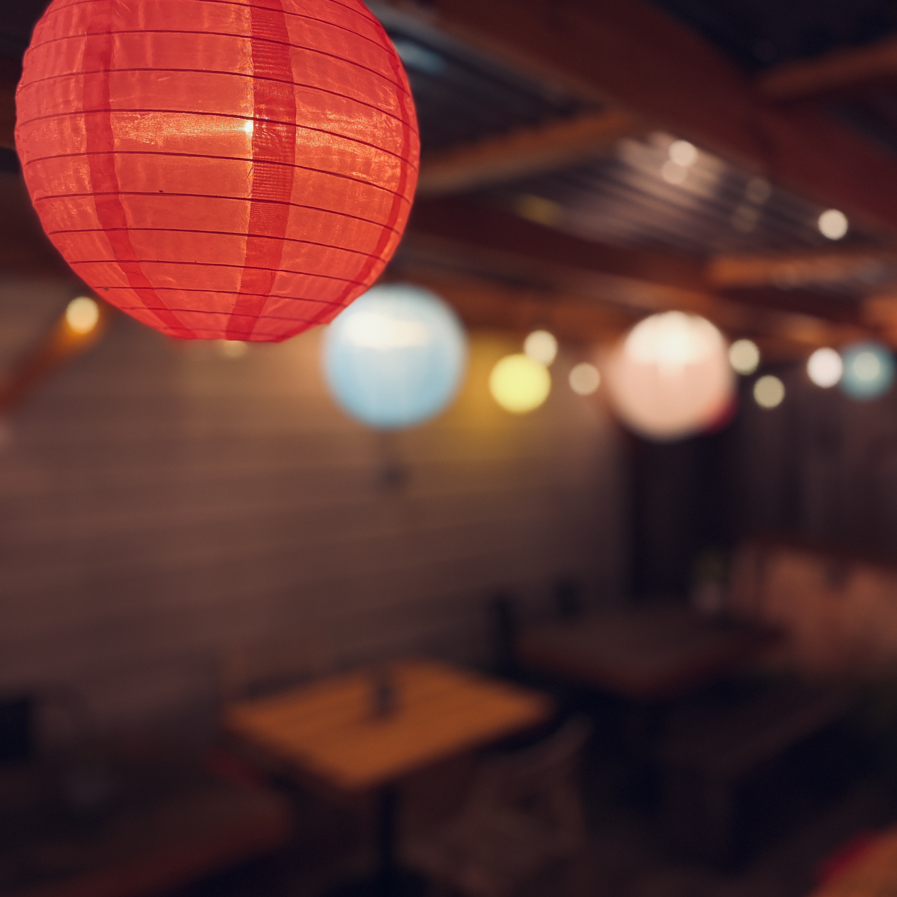 patio with wooden tables, red stools, and round Chinese lanterns