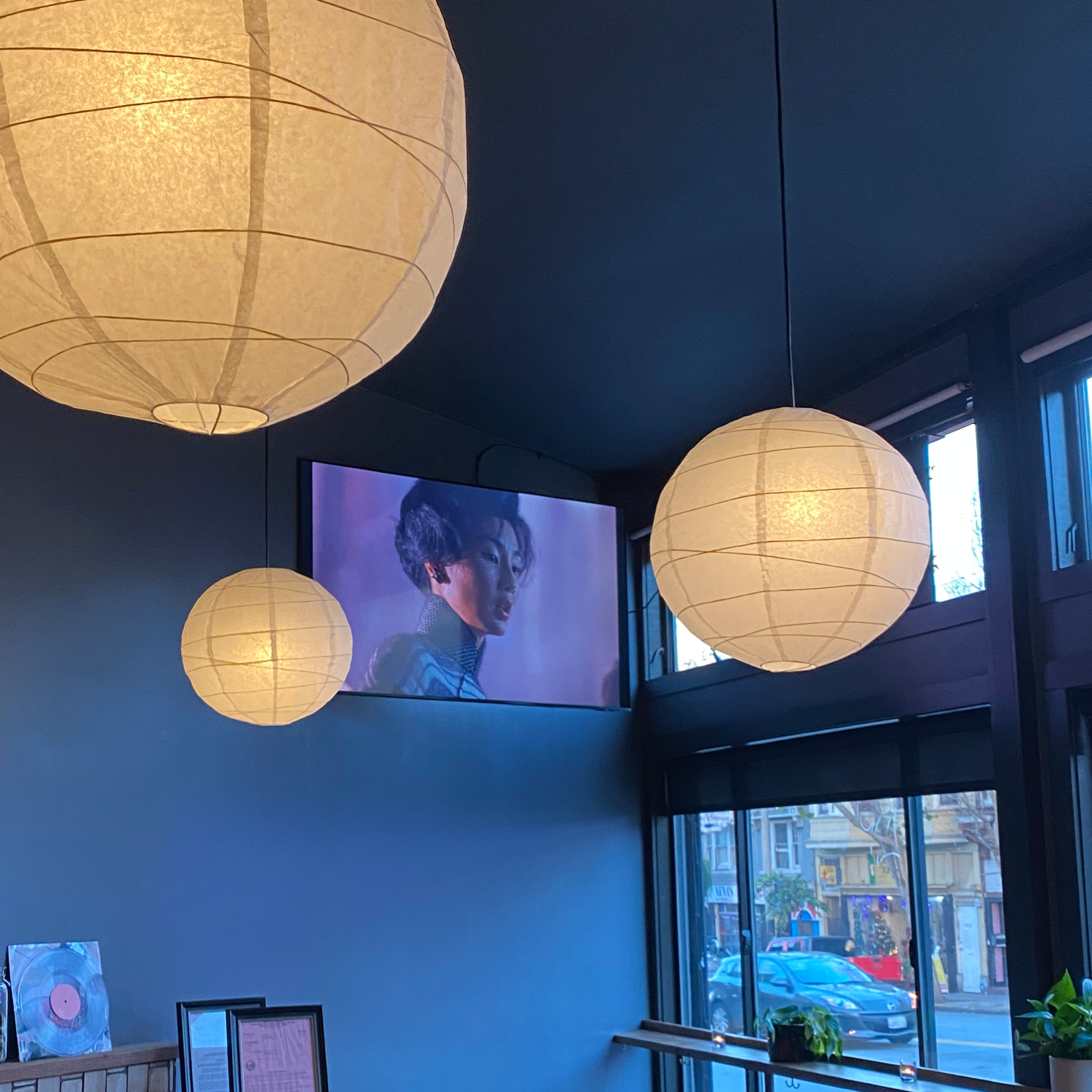 bar with rice paper ceiling pendants and a tv playing the film In The Mood For Love by director Wong Kar Wai